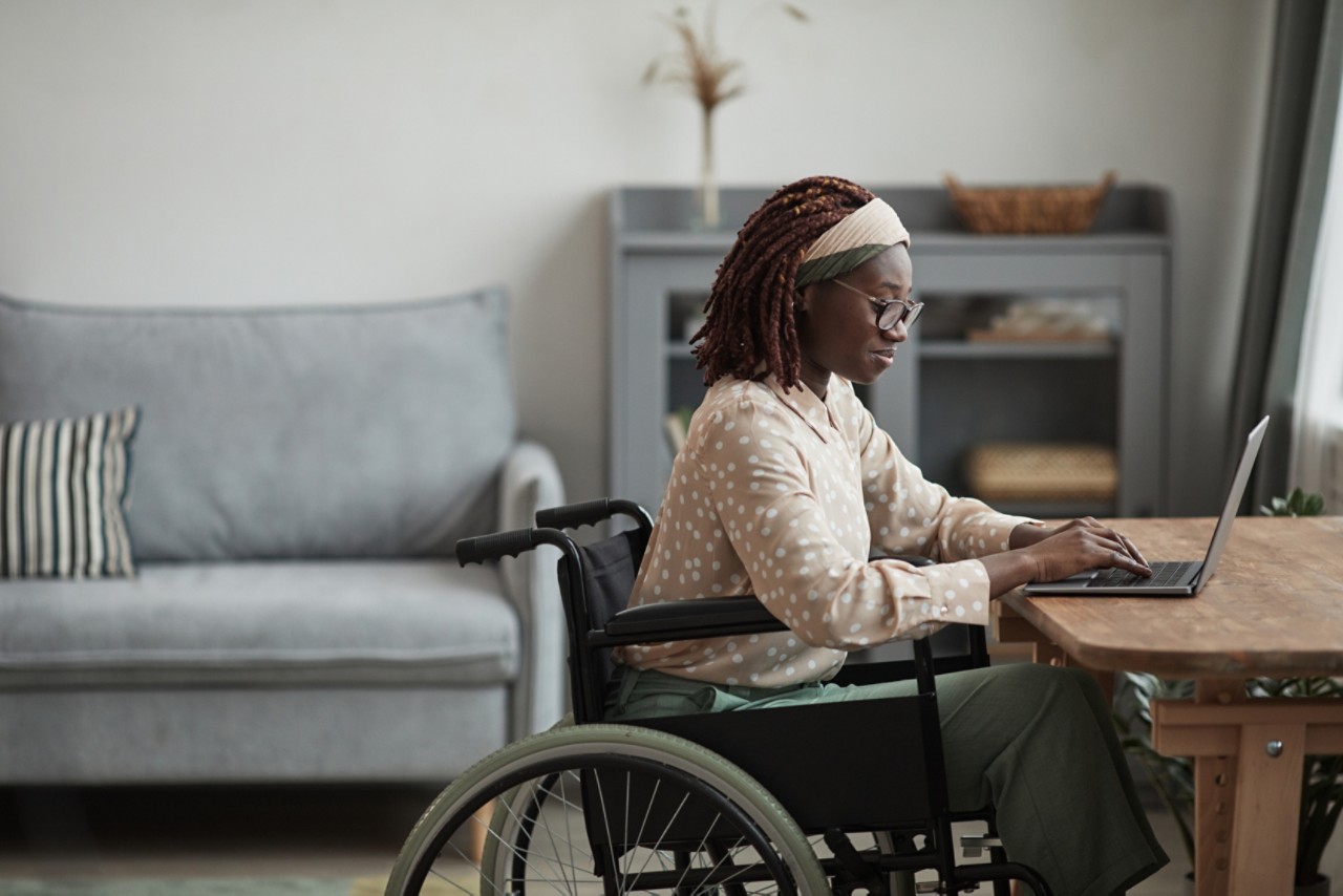 Woman in wheelchair sits at table in home