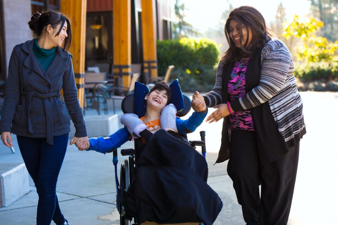 a young person in a wheelchair surrounded by loving people