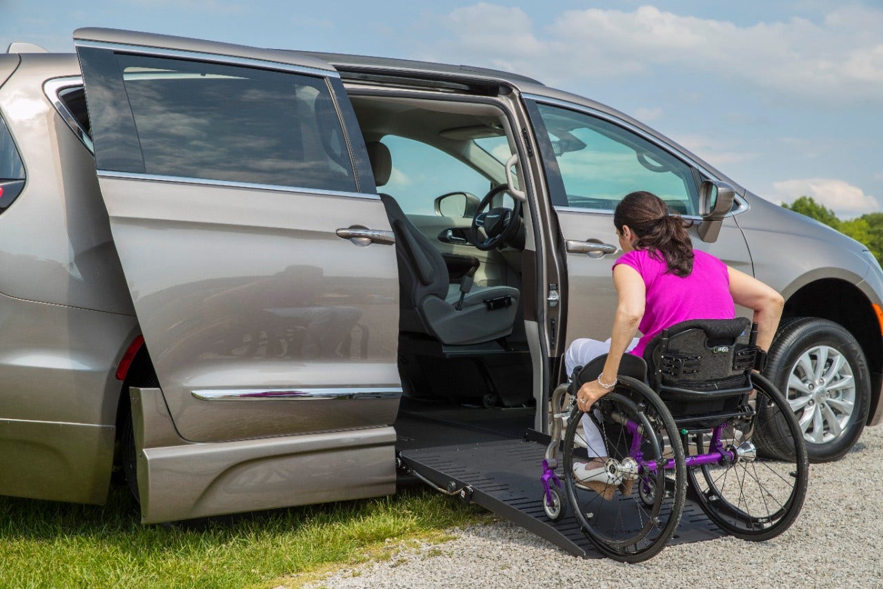 Woman in manual wheelchair acends the ramp in a BraunAbility Chrysler Pacifica Foldout