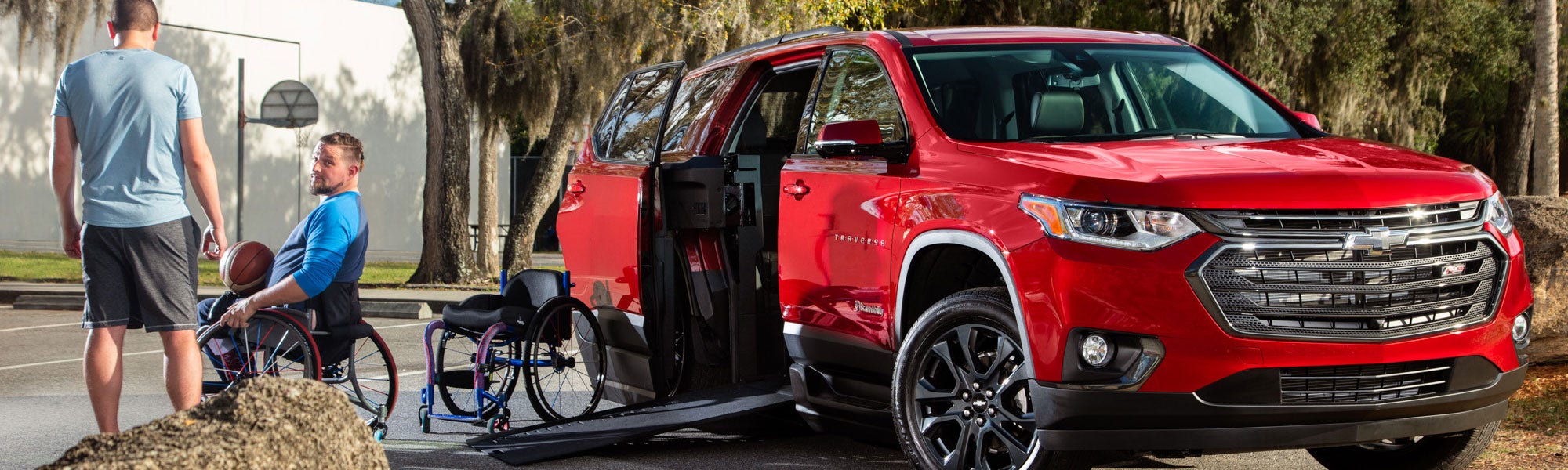 2 men standing that are getting ready to play basketball next to a chevy traverse wheelchair conversion, handicap chevy traverse, ramp for wheelchair for suv, suv with wheelchair ramp, Wheelchair accessible SUV