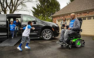 A family with a BraunAbility Chrysler Pacifica Mobility Vehcile in a driveway