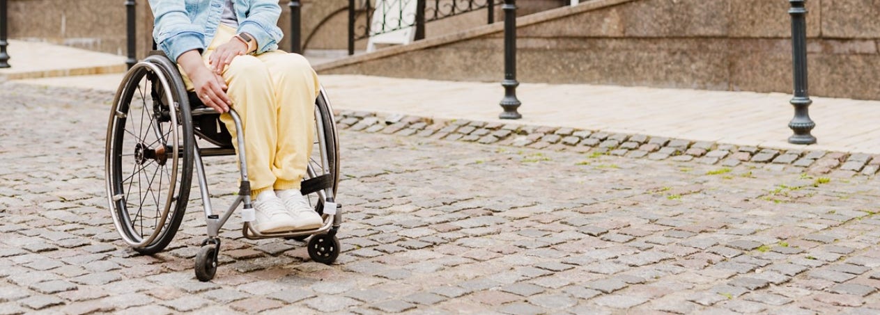 Brunette woman sitting in wheelchair on city street