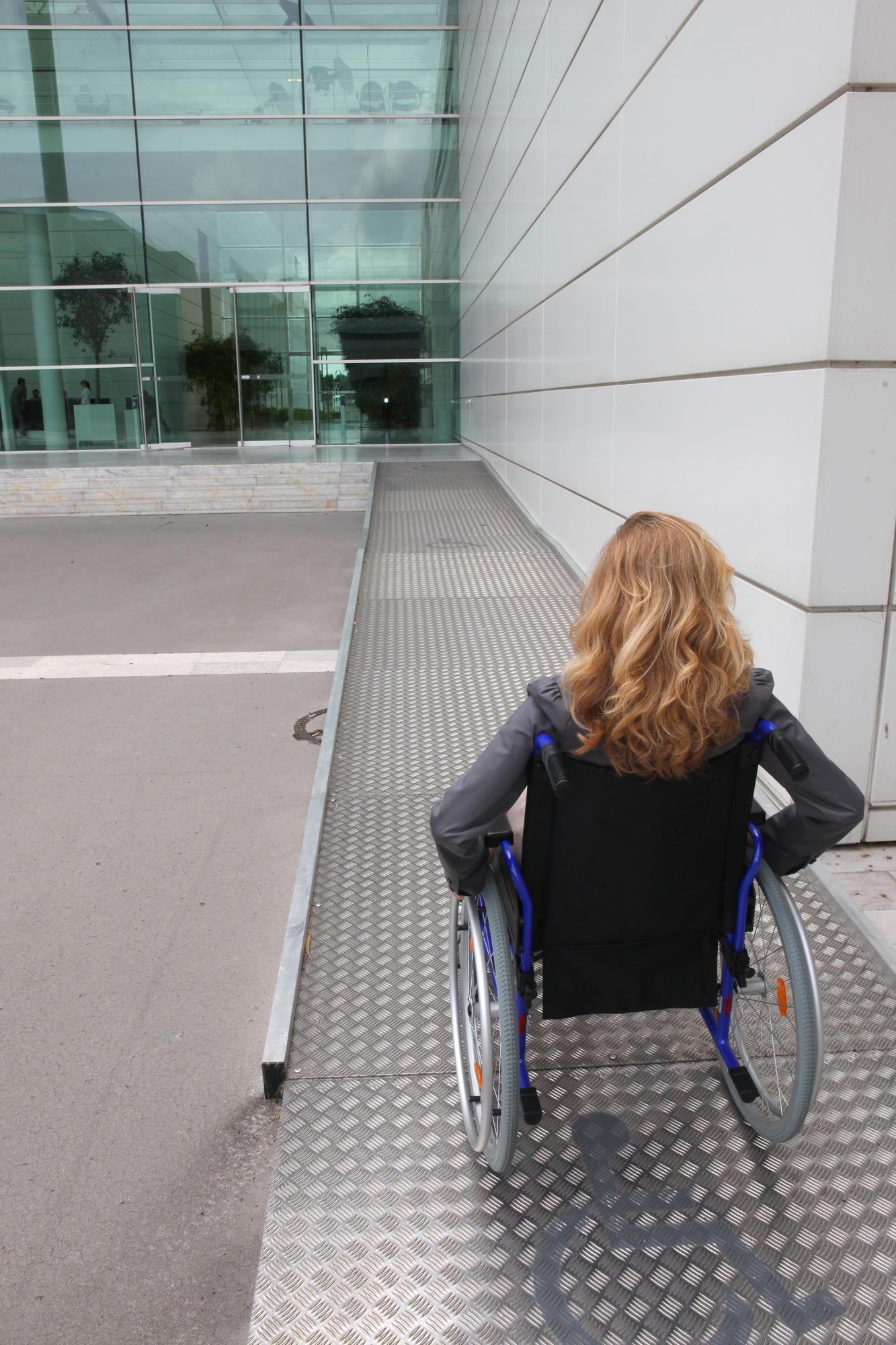 woman in a wheelchair going up a stainless steel ramps woman in a wheelchair going up a stainless steel ramps