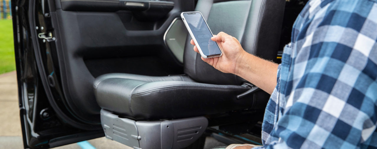 Man using phone to move accessible vehicle transfer seat