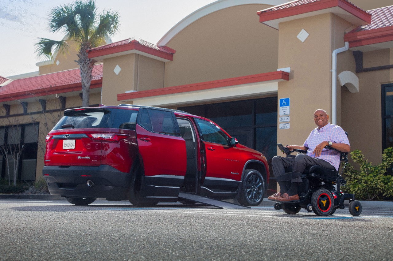 Smiling man in wheelchair next to an accessible SUV