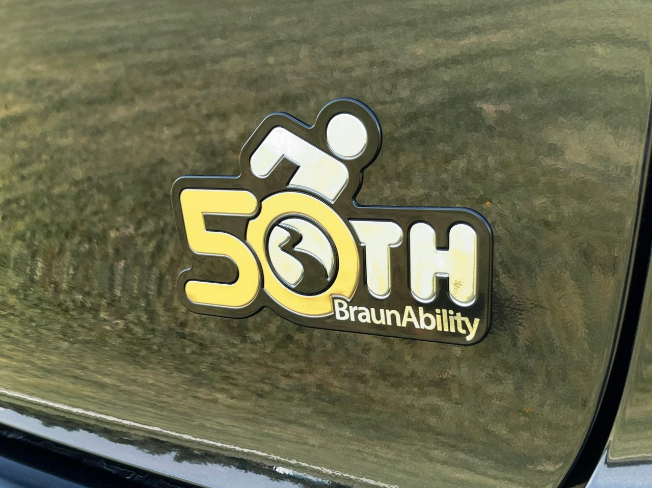 Closeup of the BraunAbility 50th anniversary logo badge on the outside door of the entervan