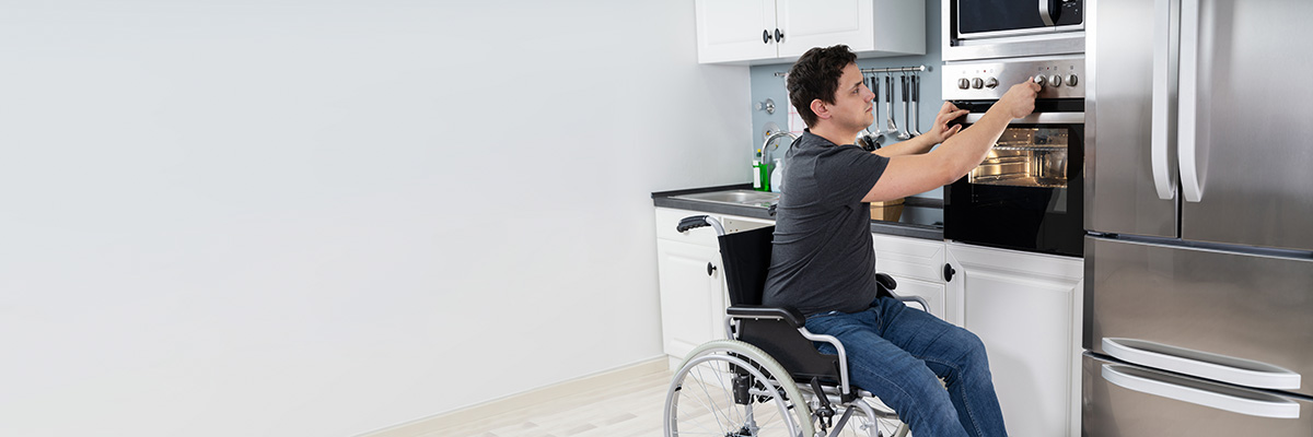 Man in a wheelchair washing dishes at a sink