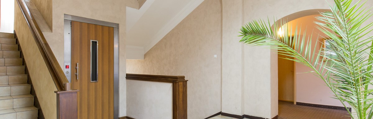 Elevator with wood door sits next to tile staircase