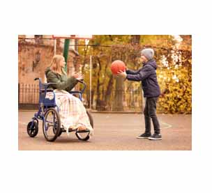 2 kids playing basketball, one of the children is in a wheelchair 