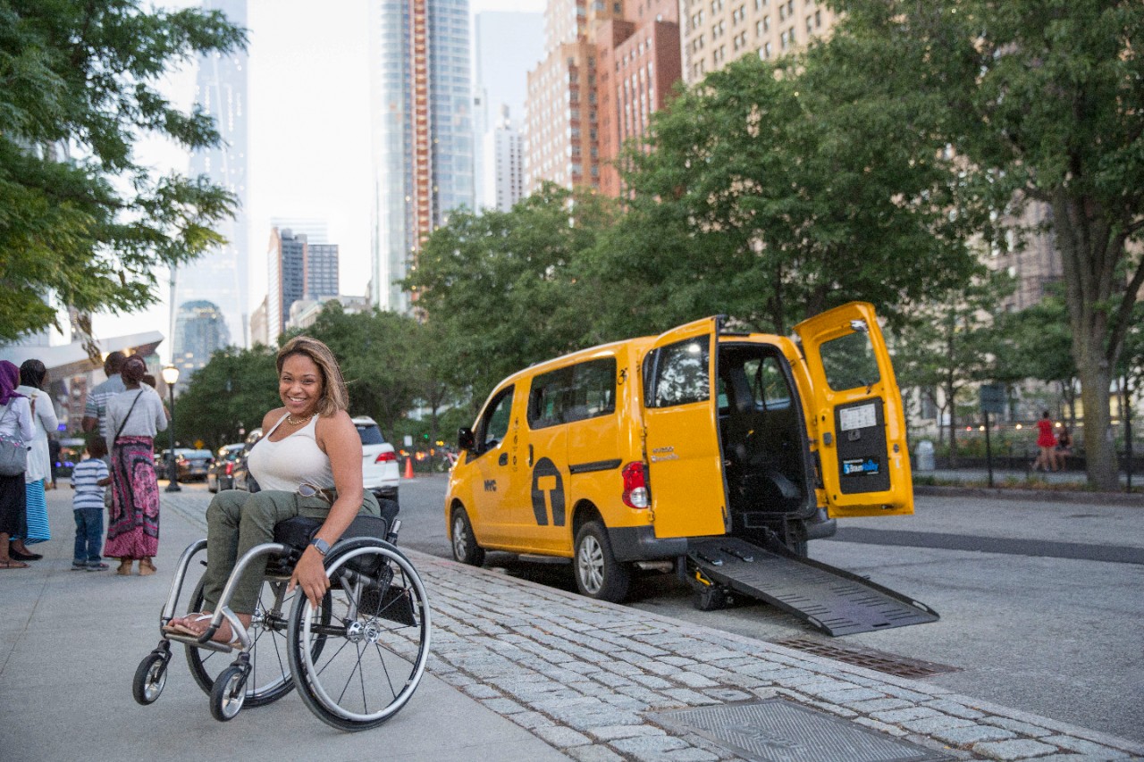 Lady in a wheelchair getting out of Taxi