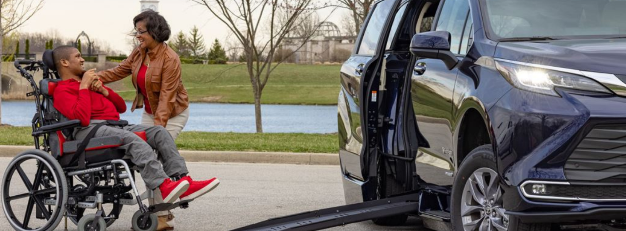 Lady helping a person in a wheelchair into a Wheelchair Accessible Van