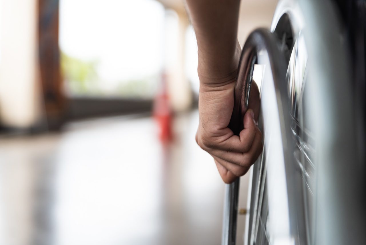 closeup disabled man hand on wheel of wheelchair