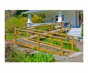 wood wheelchair ramp for house on a white house with green grass