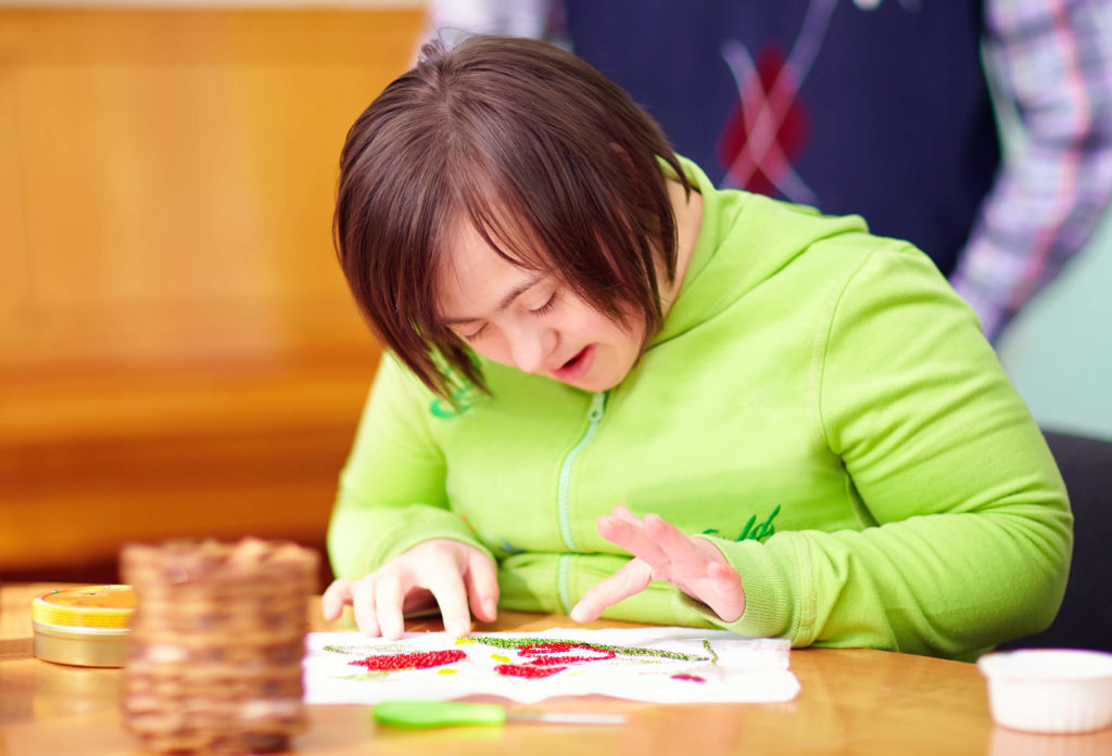 Girl with down syndrome works on a finger painting