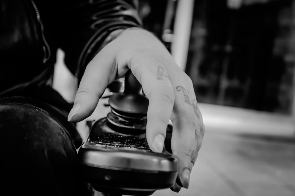 B/w hand on a power wheelchair joystick B/w hand on a power wheelchair joystick