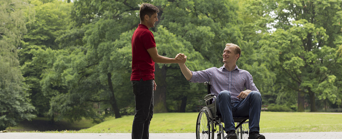Disabled man greeting friend in park