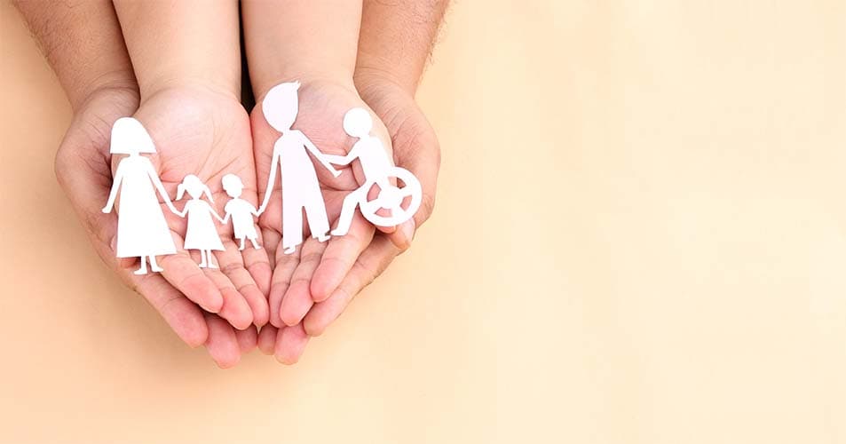 hands holding paper Cutout of different family members being together.