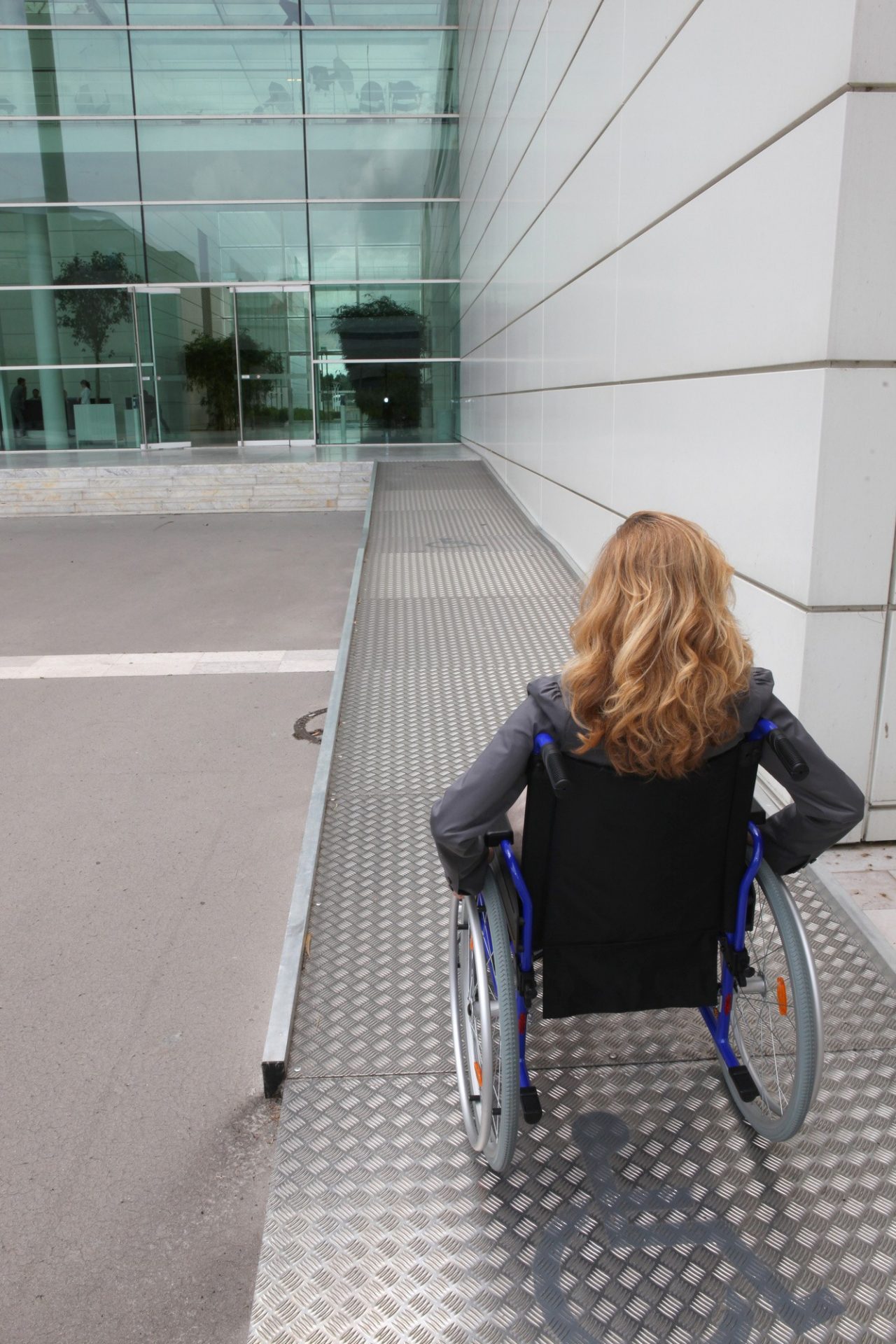 woman in a wheelchair going up a stainless steel ramps