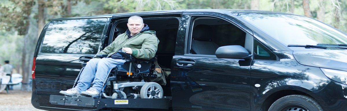 Man in power wheelchair sitting on ramp of handicap van