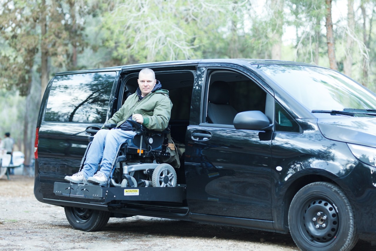 Disabled man on wheelchair standing on the car lift