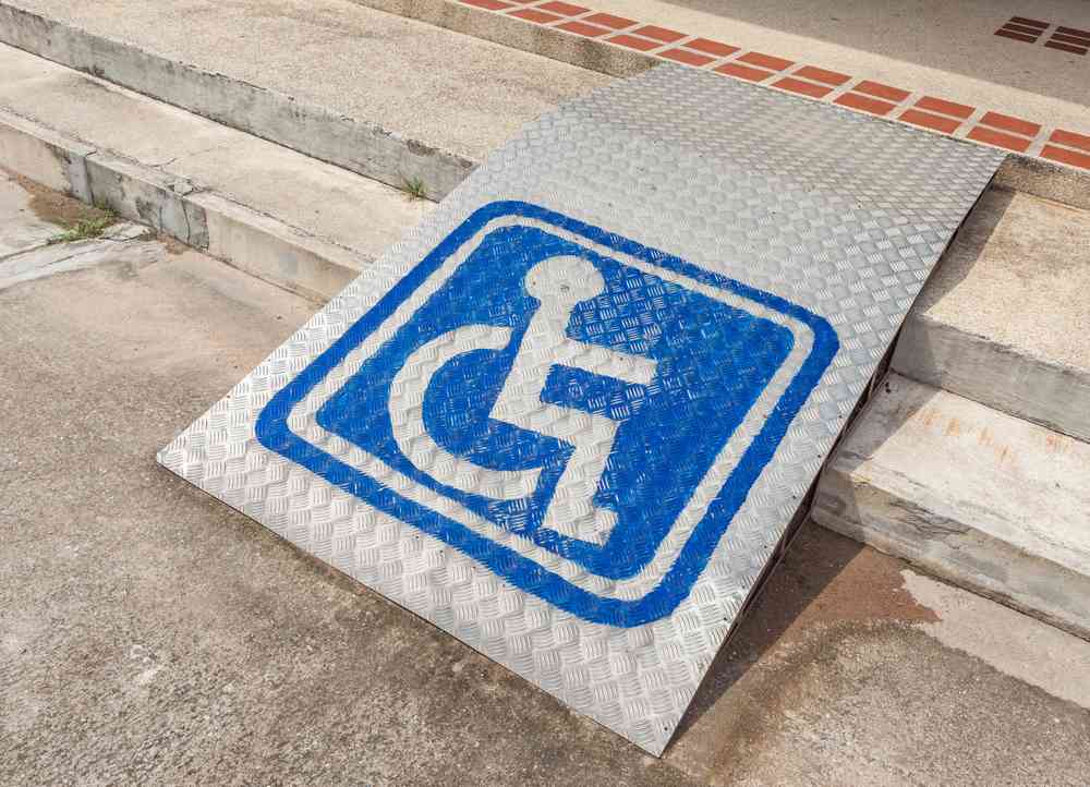 Ramped access, using wheelchair ramp with information sign on floor background for disabled people.