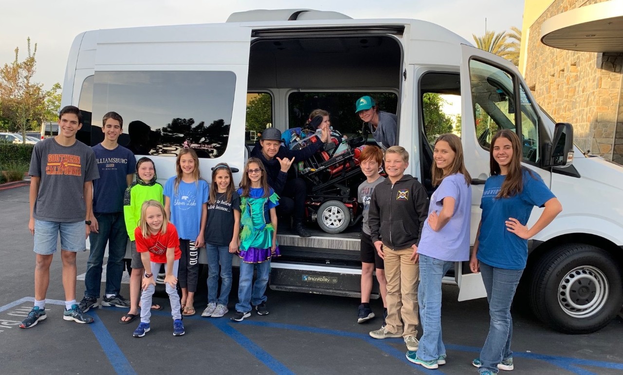 Group of students outside of a commercial bus with a BraunAbility wheelchair lift next to an access aisle