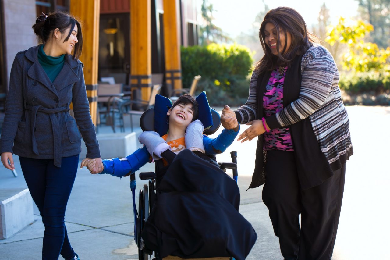 3 People a young person in a wheelchair surrounded by loving people
