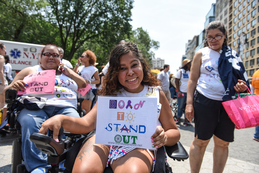 a girl holding a born to stand out sign at a rally in new york city