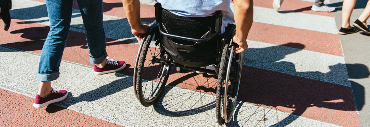 Man in a wheelchair on a crosswalk next to his friend