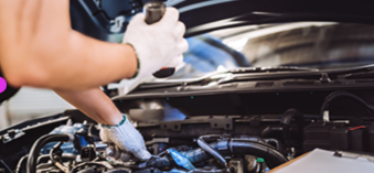 A mechanic checking a vehicle with its hood open.