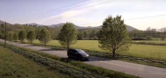 A car running on a country road with trees.