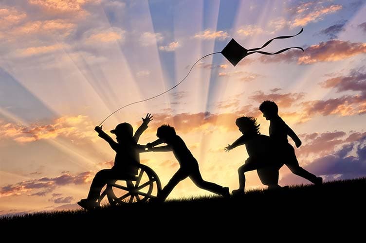 Happy boy in wheelchair playing with children and kite sunset. Concept happy child disabled