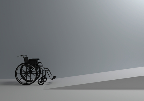 a wheelchair in a grey room getting ready to go up a wheelchair ramp