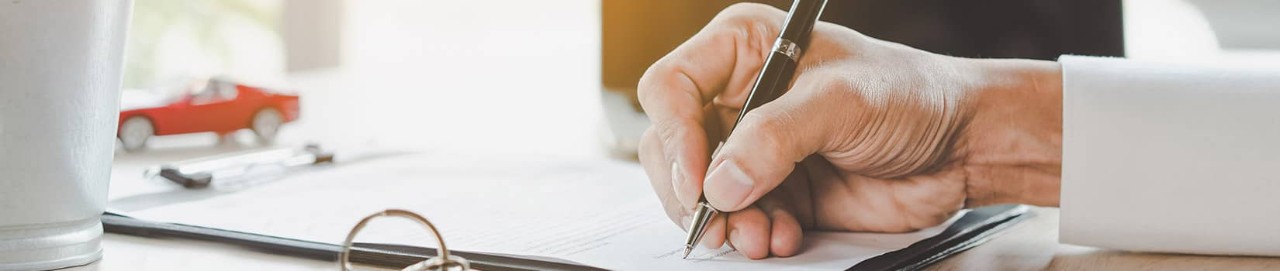 a person signing papers on a desk