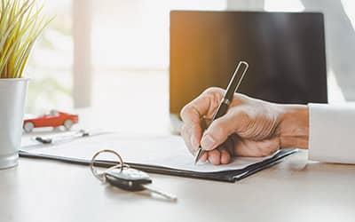 a person signing papers on a desk