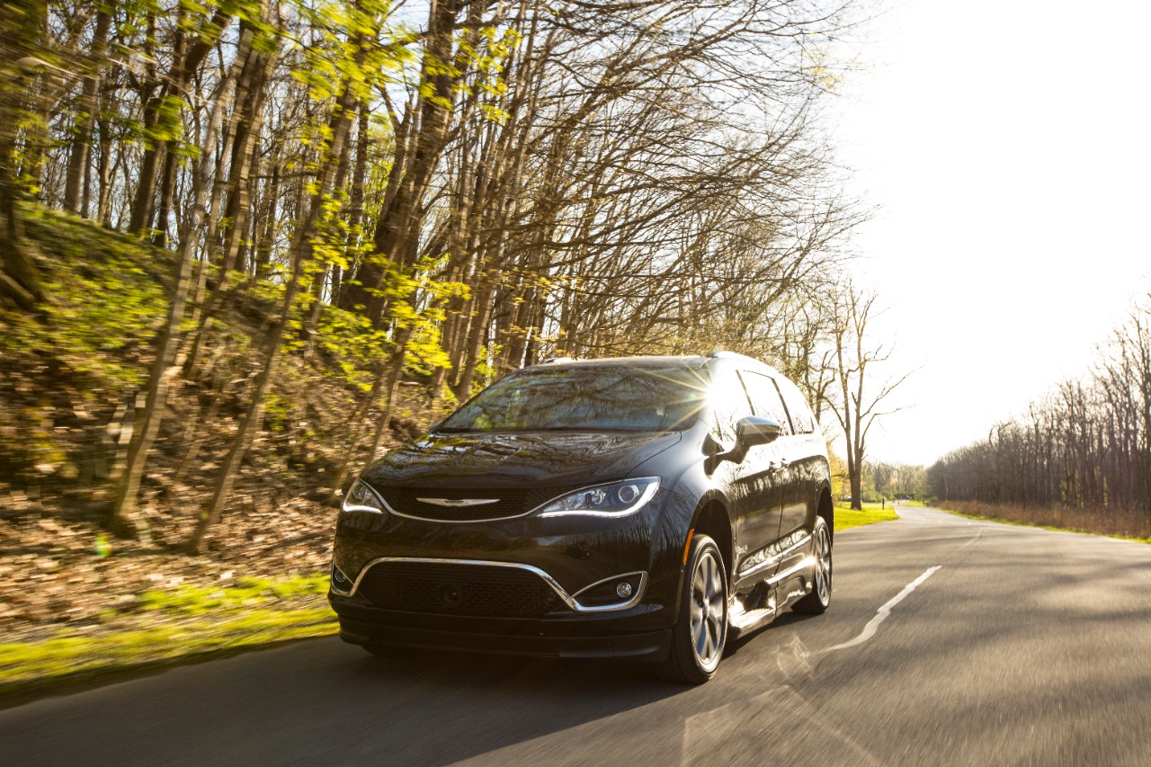 BraunAbility Chrysler Pacifica driving on a road while the sun shines overhead BraunAbility Chrysler Pacifica driving on a road while the sun shines overhead