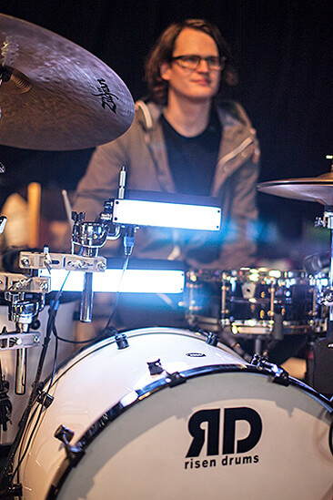 Gabriel Hagan looks on as light up sensors on his drum kit sit in the foreground Gabriel Hagan looks on as light up sensors on his drum kit sit in the foreground