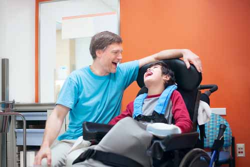 a father with his son who is using a power wheelchair 