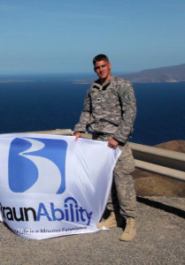 Sergent Don Perkins holds a BraunAbility flag while stationed at his deployment location