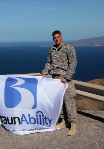 Sergent Don Perkins holds a BraunAbility flag while stationed at his deployment location Sergent Don Perkins holds a BraunAbility flag while stationed at his deployment location
