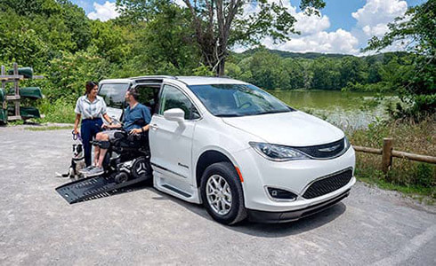 white Chrysler Pacifica sitting new to the river with a couple exiting the accessible vehicle